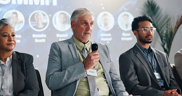 istock Conference, presentation and mature man with microphone for development, seminar or forum. Convention, speech and workshop with motivational speaker with business coaching, lecture and auditorium 2231457627