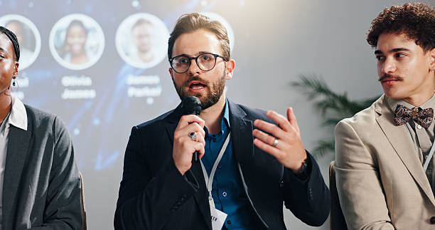istock Conference, speaker panel and man on stage for discussion, seminar FAQ and presentation. Business summit, innovation expo and people with speech for tradeshow, event and entrepreneur convention 2231457628