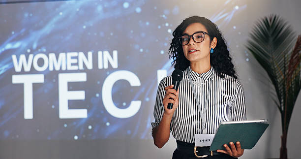 istock Business woman, speaker and presentation with tablet or mic at seminar for tech summit at workplace. Female person, presenter or speech with technology or screen for corporate tradeshow or convention 2231457657