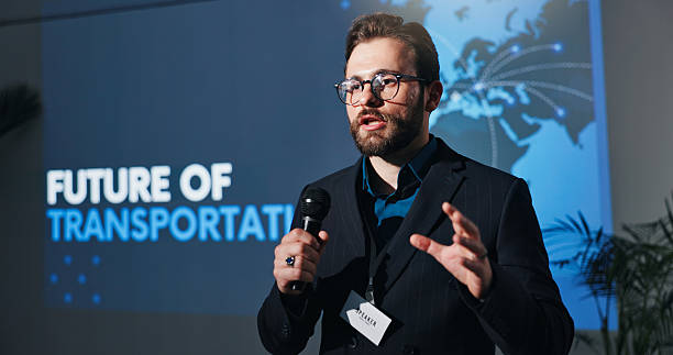 istock Conference, microphone and speech with man on stage for presentation on future of transportation. Auditorium, development and forum with corporate speaker on podium for innovation in travel symposium 2231457670