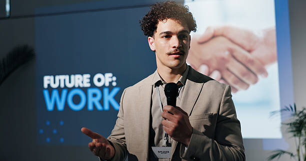 istock Business, microphone and speech with man in auditorium for presentation on future of work. Seminar, symposium and trade show with guest speaker on podium or stage for job change or transformation 2231457704