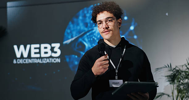 istock Man, tablet and mic for presentation with web3, decentralization and blockchain by screen for future. Person, speaker and touchscreen with app, innovation and discussion on stage at tech convention 2231457711