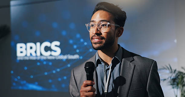 istock Microphone, seminar and speech with business man in auditorium for presentation on BRICS union. Development, symposium and workshop with speaker on podium or stage for economic conference and forum 2231457719