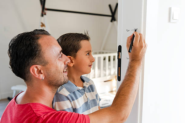 istock Millennial Father measuring son's height on door 2231461160