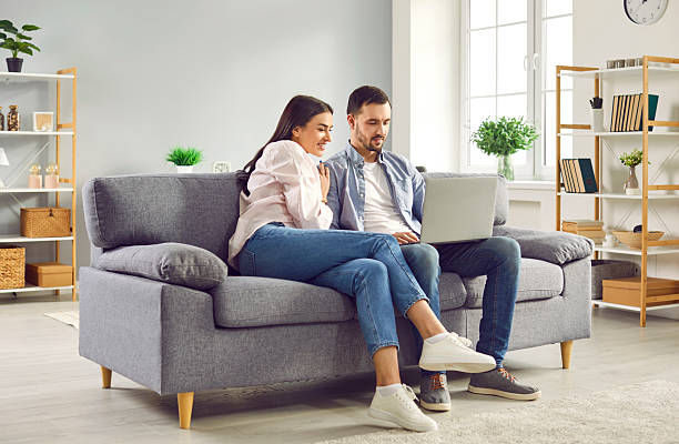 istock Happy family couple using laptop computer sitting on couch at home 2231463895