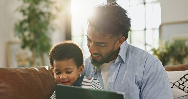 istock Father, boy and happy with tablet on sofa for elearning video, bonding and relax in living room. Man, dad and child with tech, game or streaming subscription for education cartoon at family home 2231464672