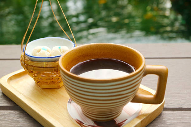Cup of Black Coffee Served with aromatic Thai tiny biscuits called Kleeb Lamduan, meaning Lamduan flower's petals