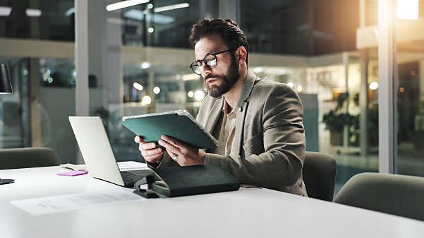 istock Businessman, night or tablet with research for project deadline or development in conference room. Man, analyst and working late with technology or laptop for corporate strategy or planning in office 2231468616