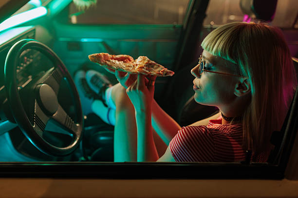 istock Trendy woman with pizza in car. 2231470469