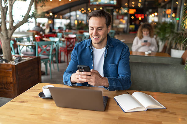 istock Young businessman using smartphone and working on laptop in cafe 2231470571
