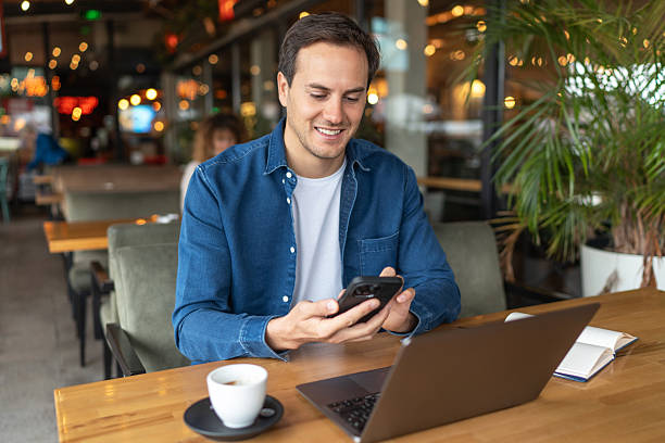 istock Young adult man using smartphone and laptop in cafe 2231470610
