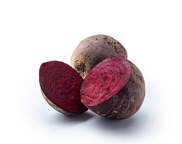 One Whole beetroot next to one cut in half on a white background, studio shot.