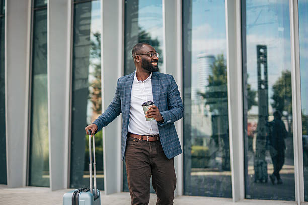 istock Smiling businessman walking with suitcase and coffee 2231478155
