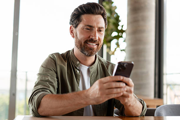 istock Smiling businessman using smartphone in a restaurant 2231478343