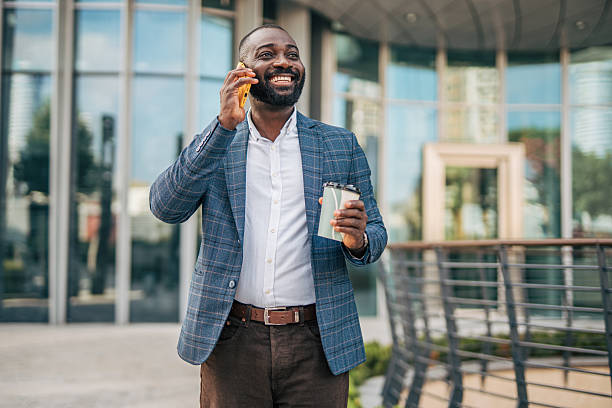 istock Smiling businessman walking and talking on phone holding coffee 2231478372