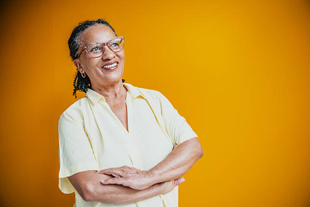istock Senior woman smiling confidently in a bright yellow studio with a cheerful expression 2231478577
