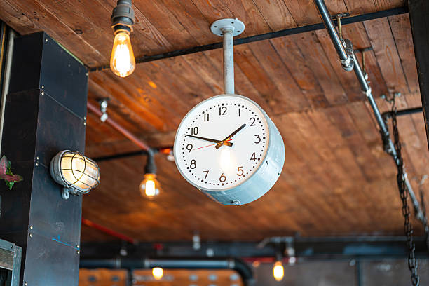 A classic style ceiling round clock which is pointing in the afternoon time, that installed on the wooden ceiling. Interior decoration object photo, close-up.