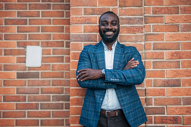 istock Confident businessman smiling with folded arms by brick wall 2231478842
