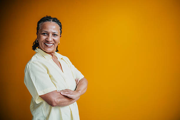 istock Senior woman smiling confidently against a vibrant yellow background in a studio setting 2231478946