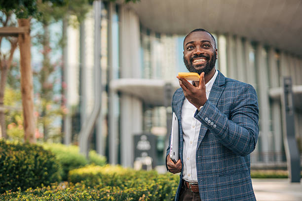 istock Smiling businessman using voice assistant on smartphone outdoors 2231479020