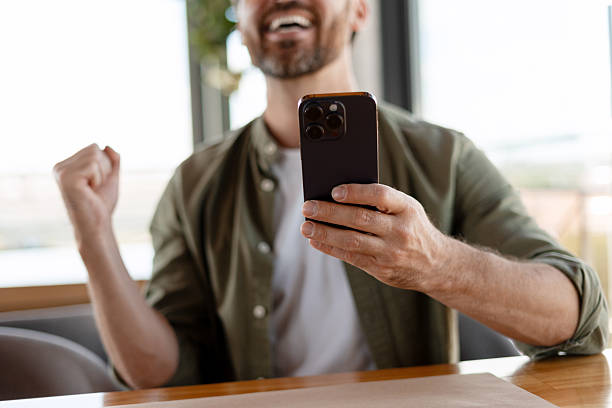 istock Excited man celebrating success while looking at smartphone 2231479118