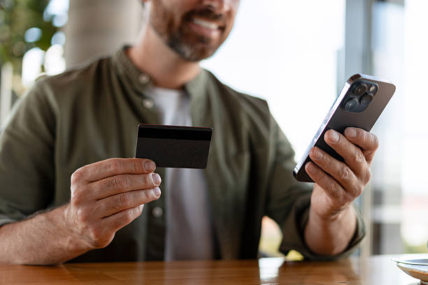istock Man paying with credit card using smartphone at cafe 2231479305