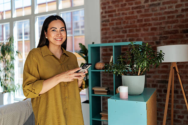 istock Smiling woman holding phone, looking at the camera 2231479448