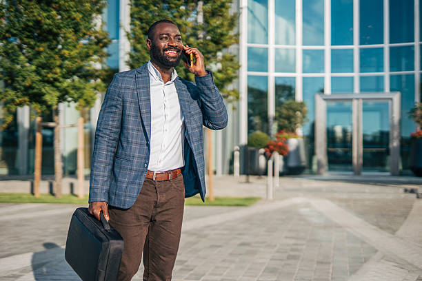 istock Smiling businessman walking and talking on phone outside office 2231479532