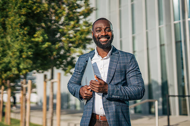 istock Smiling businessman holding laptop in urban setting 2231479593