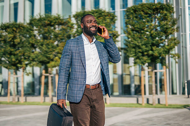 istock Smiling businessman walking and talking on phone outside office 2231479678