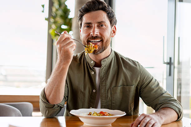 istock Man eating pasta in a restaurant, enjoying his meal 2231479792