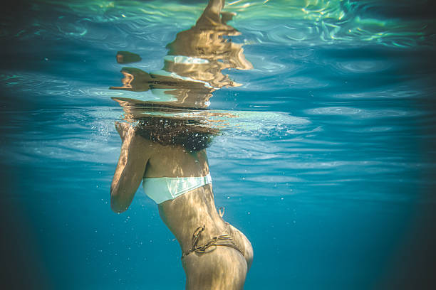 istock Tranquil Female Swimming Slowly In Bright Waters With Sunlight Filtering Gently From Above 2231479979