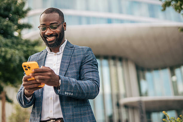 istock Smiling businessman using smartphone in front of office building 2231480436