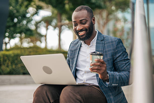 istock Smiling businessman working on laptop while enjoying coffee outdoors 2231482117