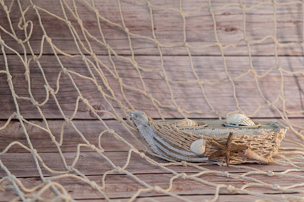 istock Litte boat by rope net with wood background 2231484218