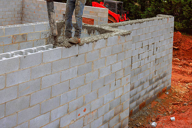 istock Construction worker pouring cement to build wall at construction site in broad daylight 2231485331