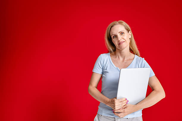 istock Confident woman holding a blank board in a modern studio with a vibrant red background 2231486997