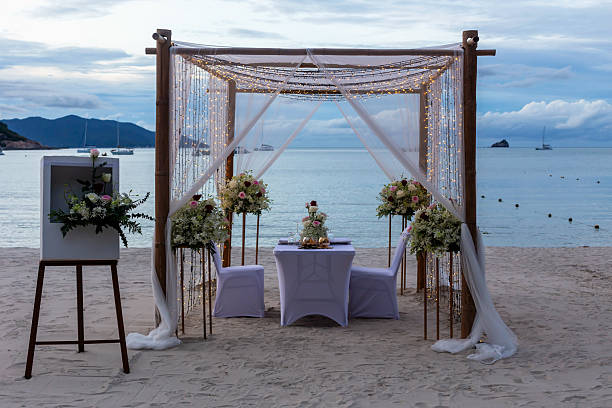 istock Beach wedding ceremony setup with floral decorations and elegant drapery under cloudy sky 2231489278