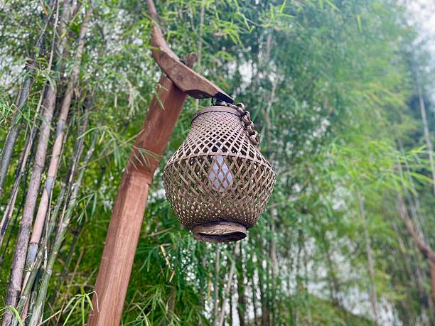 A detailed view of a traditional bamboo woven ceiling featuring geometric patterns and a central rattan lamp. The intricate craftsmanship and warm tones highlight authentic Indonesian interior design.
