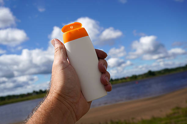 Female hand applying sunscreen cream on legs, she has vitiligo.