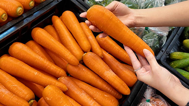 istock A person is holding a large carrot in a grocery store 2231502004