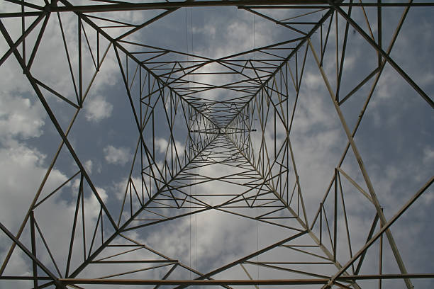 A view looking up through a tall metal tower structure against a cloudy sky