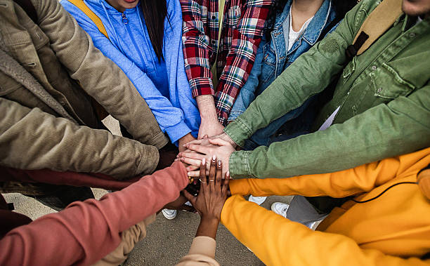istock Diverse group of young friends stacking hands outdoors showing support and unity 2231505346