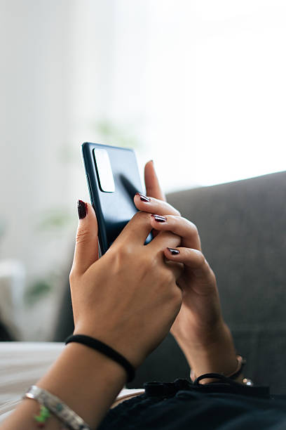 Woman relaxing on sofa and using smartphone at home