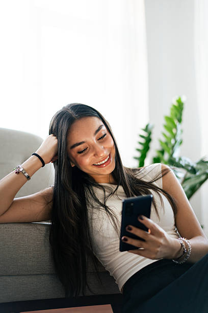istock Young woman relaxing on sofa using smartphone at home 2231516188