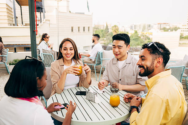 istock Four multiracial people enjoying drinks on rooftop terrace on weekend, woman talking with friends listening 2231519123