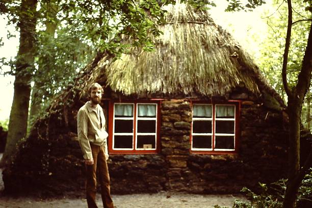 A close-up view of a wooden-framed window set within a thatched roof wall, warmly illuminated by the golden glow of sunset, showcasing traditional architectural methods and rustic charm.