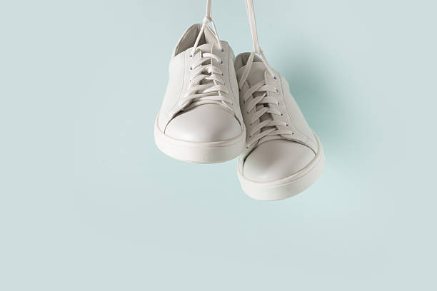 istock New white sneakers hanging against light blue background. 2231521333