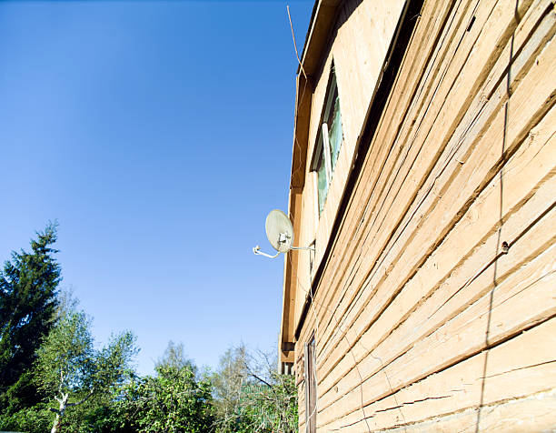 a satellite dish on the wall of wooden house, daytime shot
