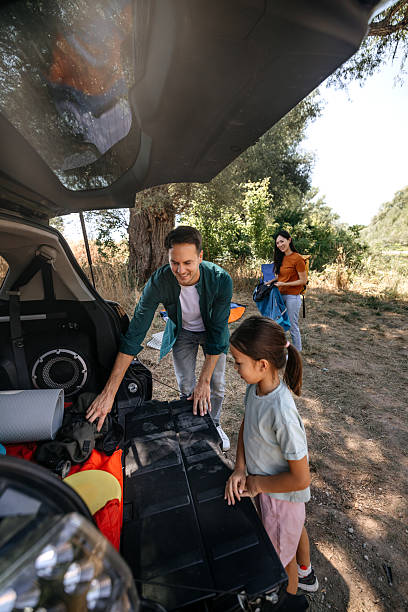 Young family unpacking car trunk for picnic